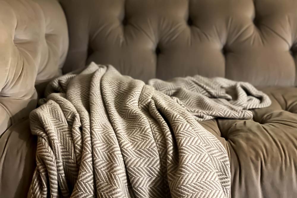 Comfortable nook on tufted sofa with herringbone print cashmere throw blanket