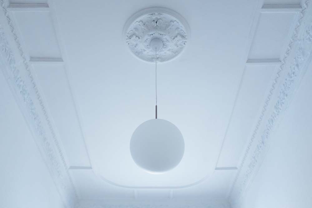 Low angle view of pendant light hanging from white ceiling at home